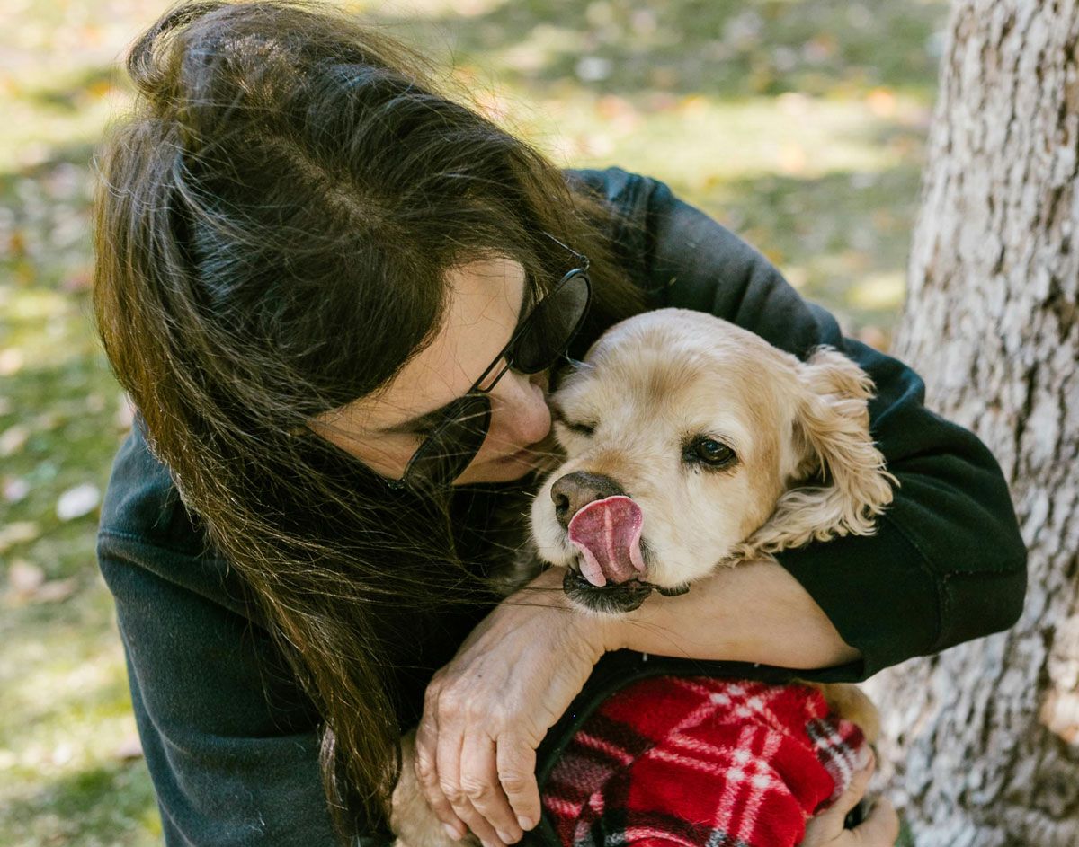 Una mujer abraza a un perro mayor